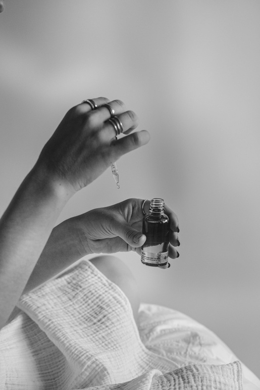 Grayscale Photo of Person Holding Bottle